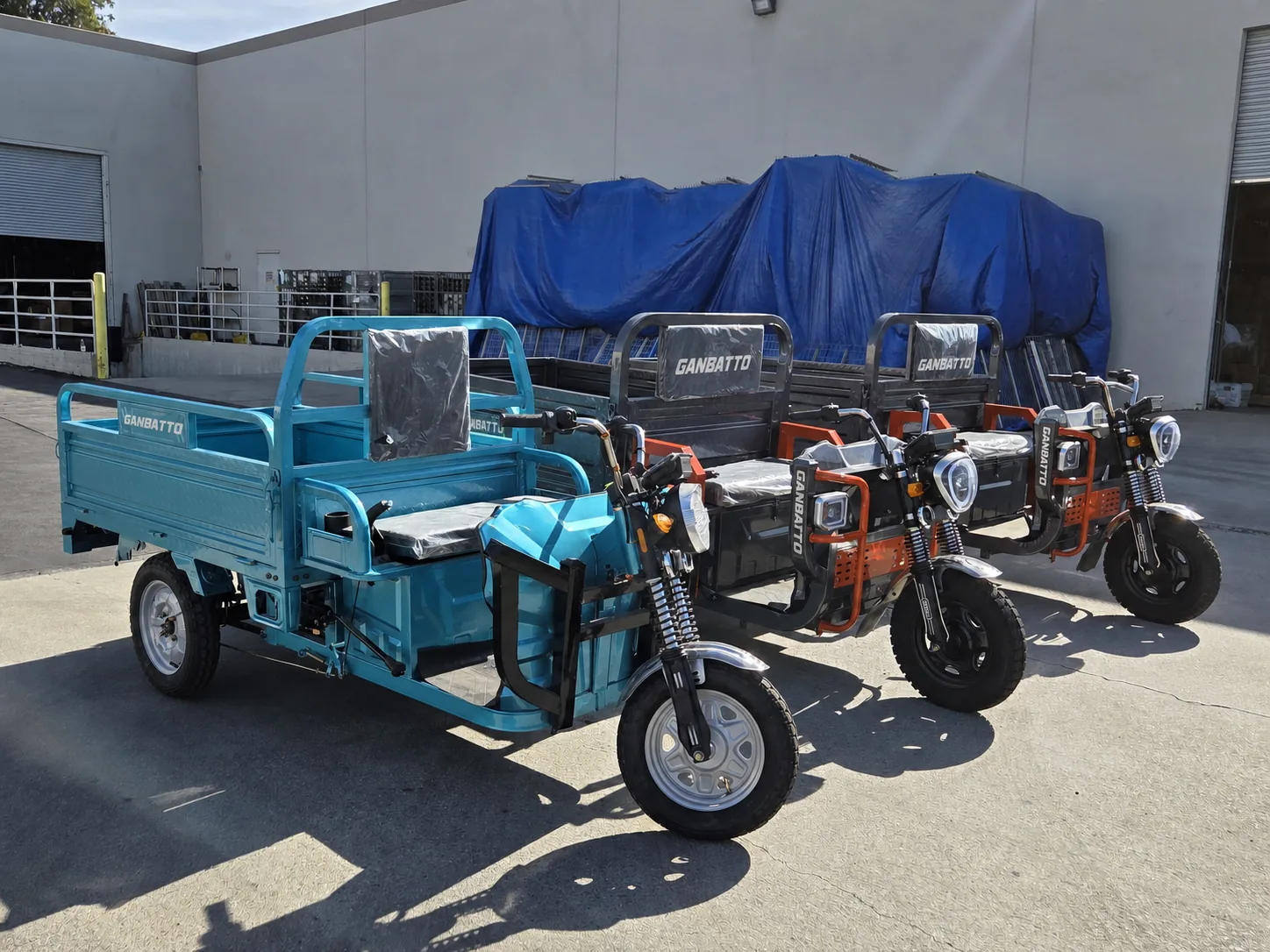 Blue and orange Ganbatto cargo tricycles in a fleet lineup