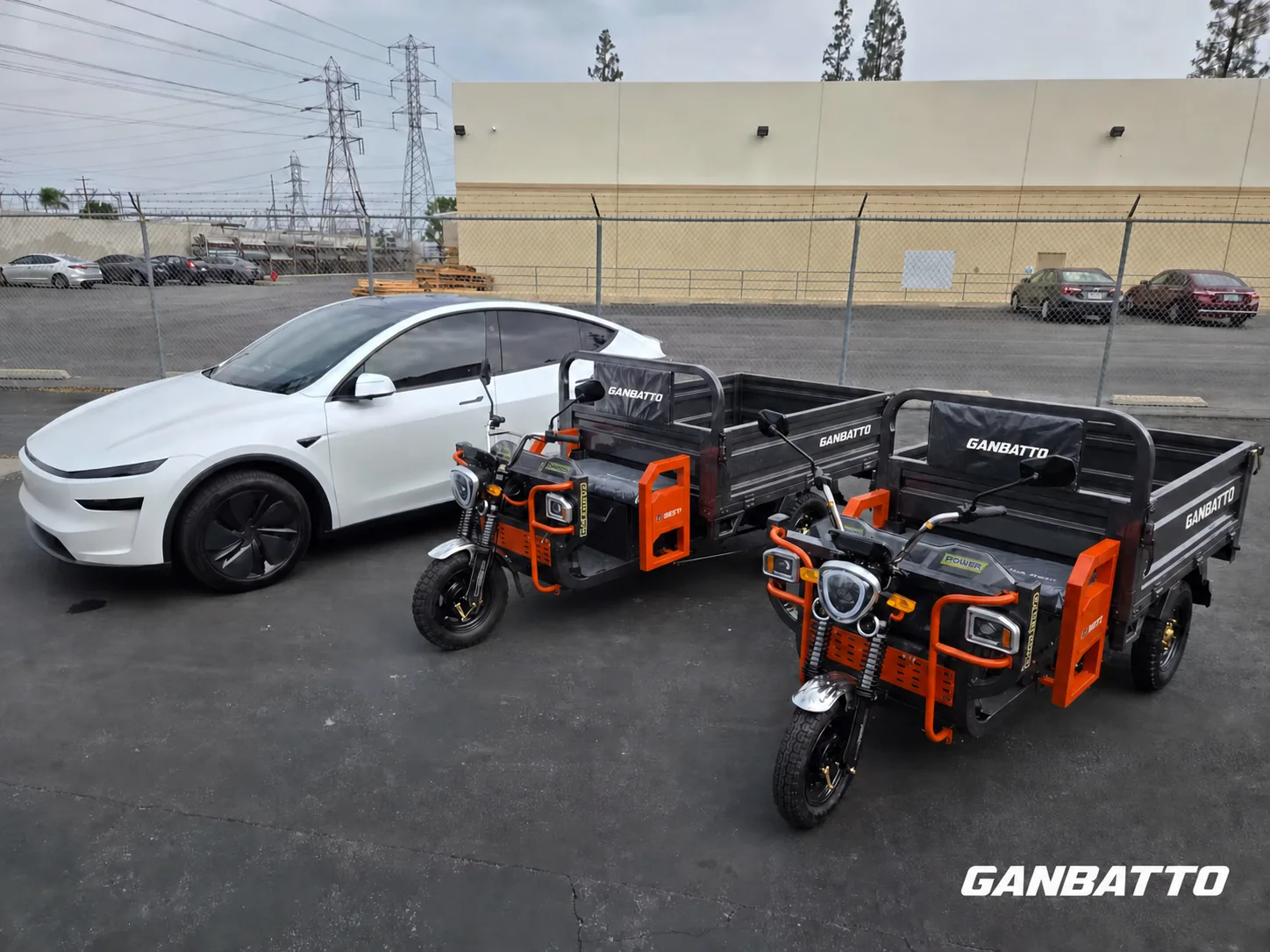 Two Ganbatto cargo tricycles parked beside a passenger vehicle